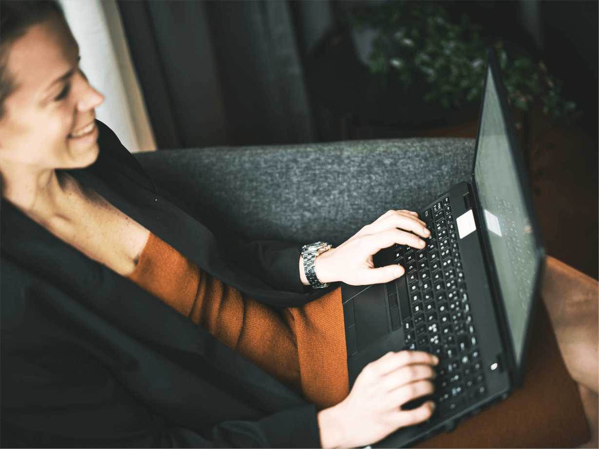 Kvinna sitter i soffa med dator i knät