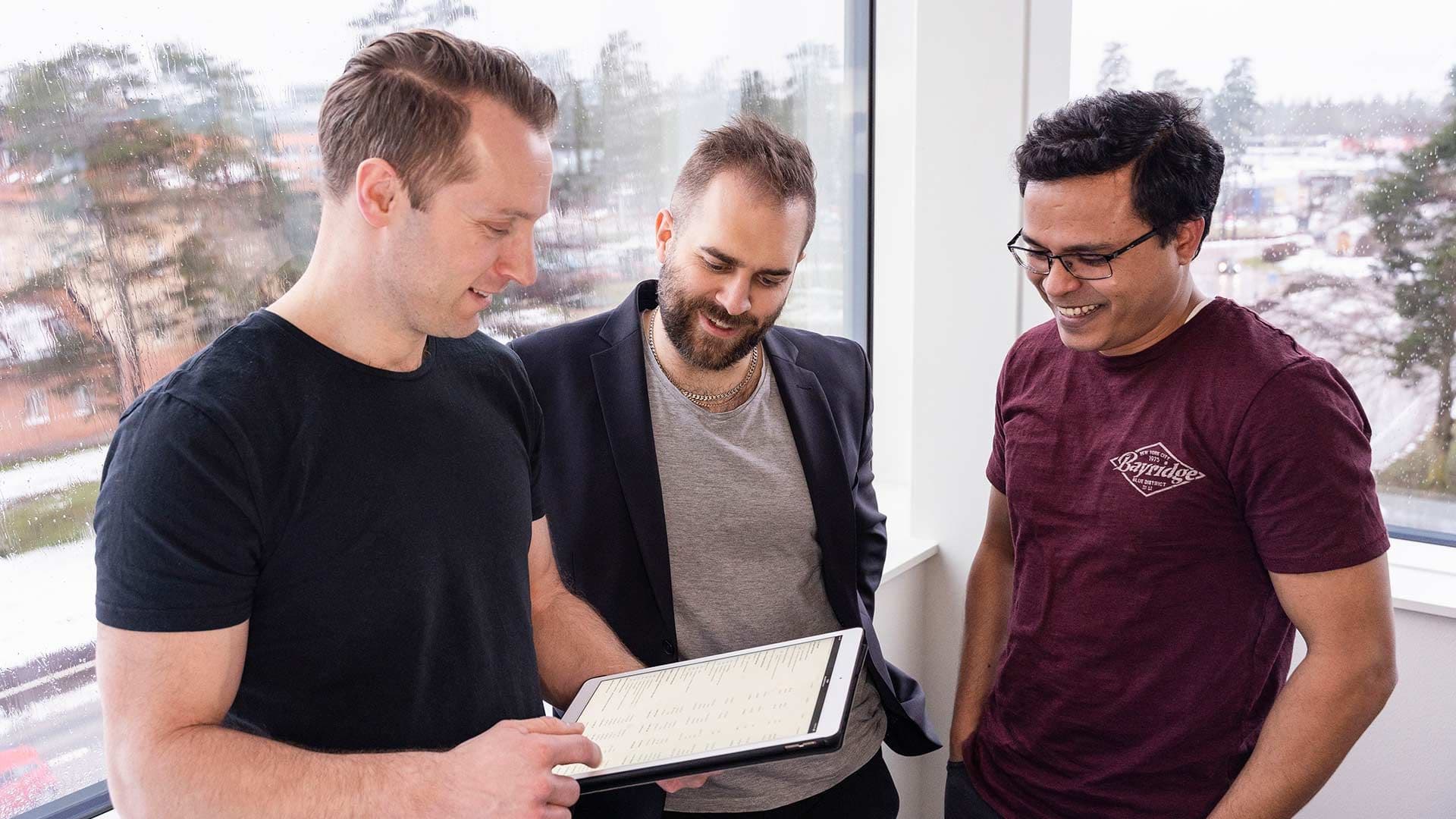 Grupp av medarbetare som tittar på en surfplatta.
