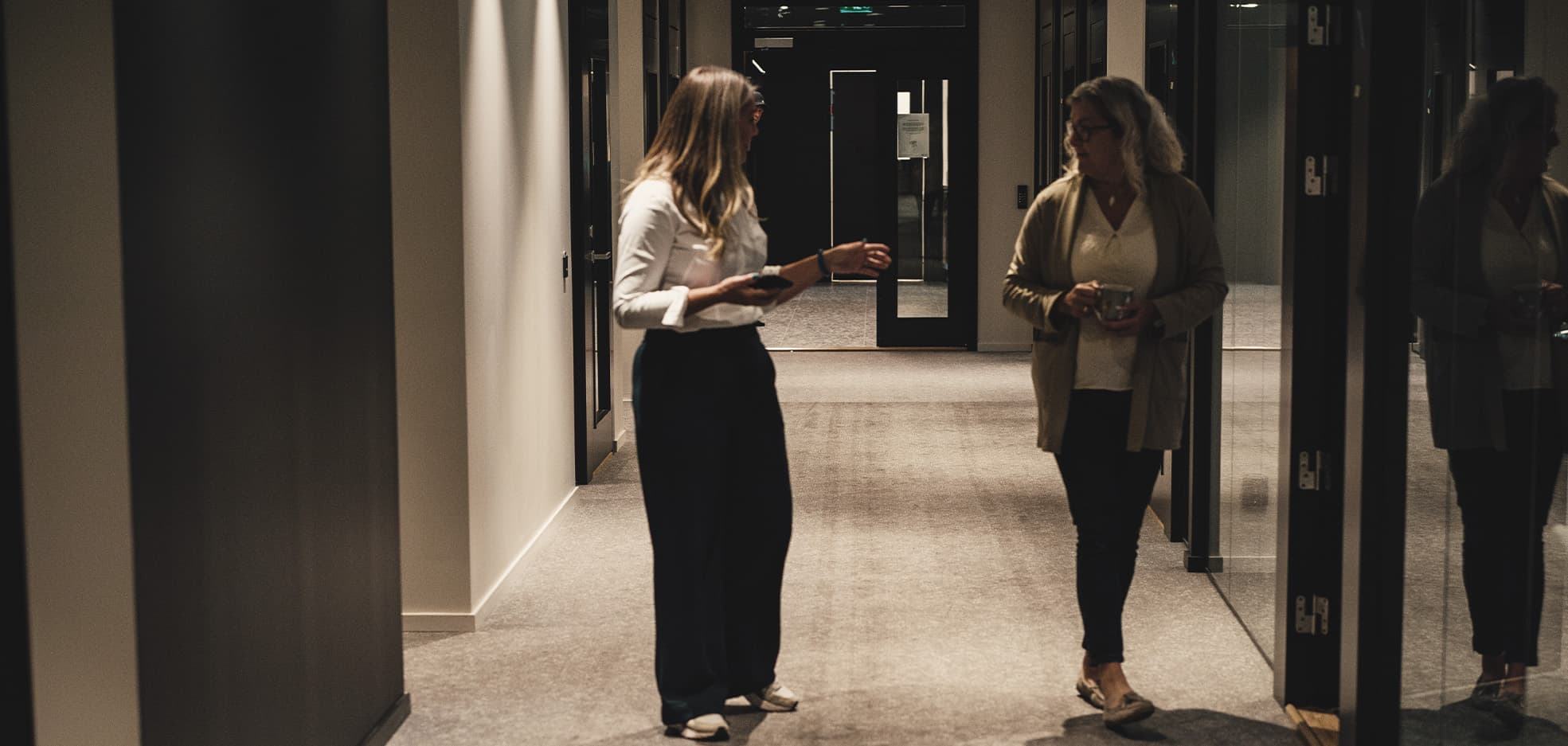 Två kvinnor står i en korridor och pratar