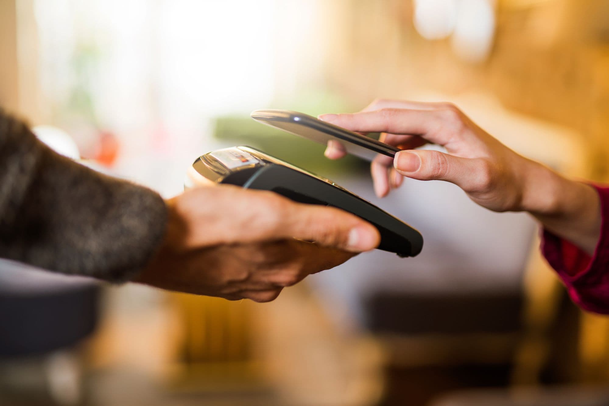 En person som tar betalt genom sin mobiltelefon mot en kortläsare
