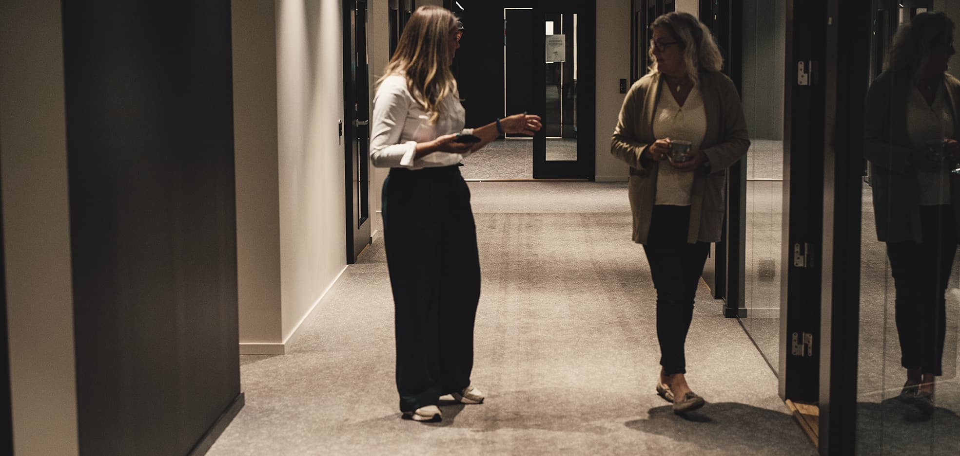 Två kvinnor står i en korridor och pratar