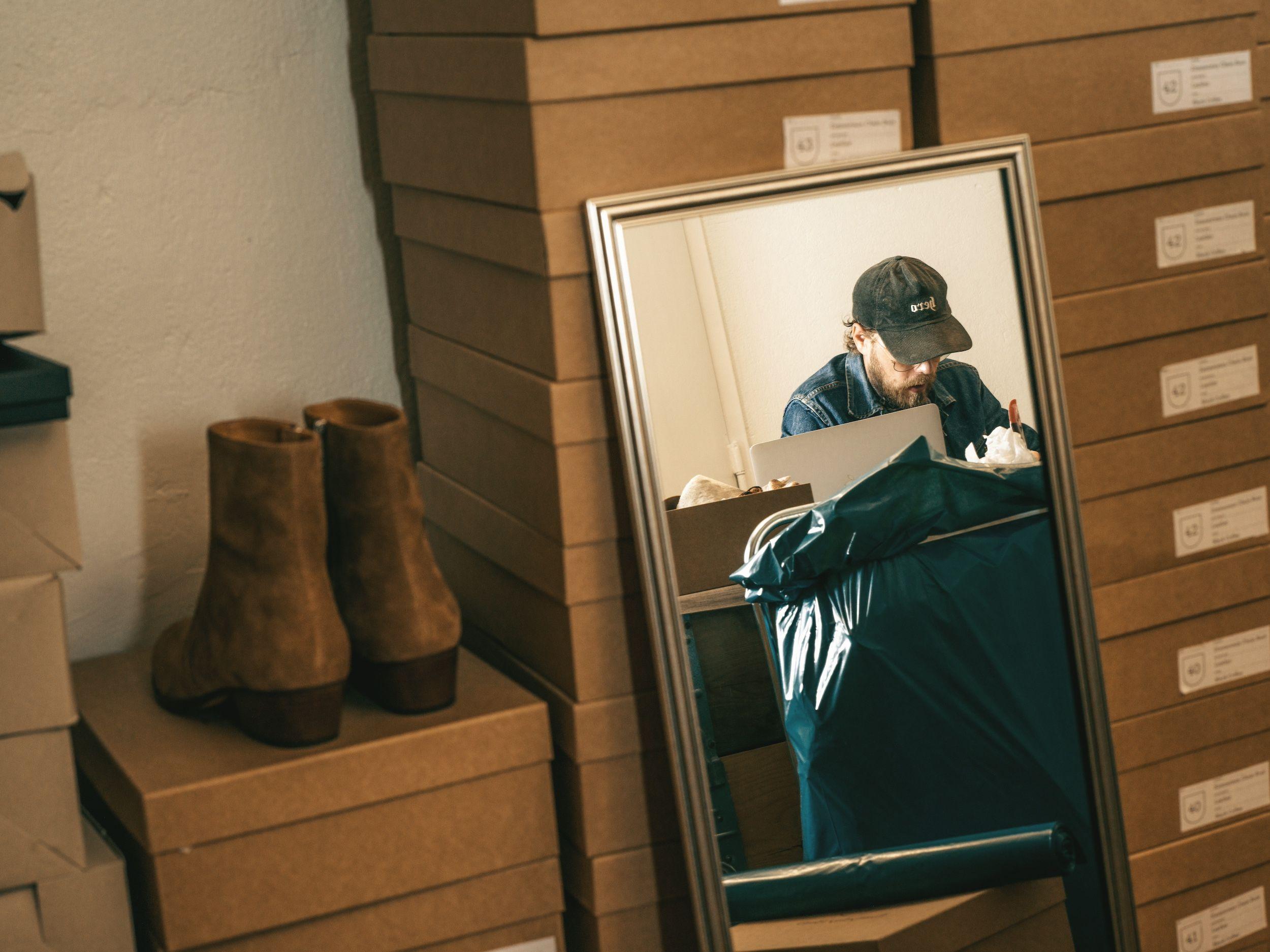 En person som sitter och arbetar och reflekteras i en spegel
