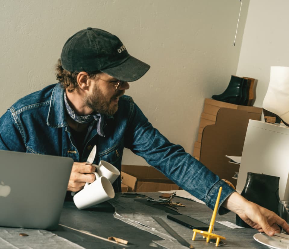 En person som sitter vid ett skrivbord och håller i två kaffekoppar